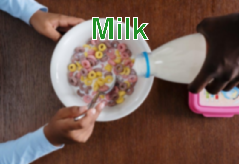 a person pouring milk on bowl of cereals